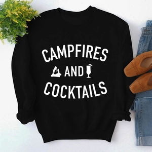 Flat lay of black sweatshirt with Campfires and Cocktails print and lifestyle props