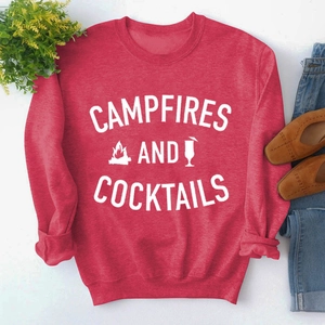 Flat lay of a red sweatshirt with Campfires and Cocktails print and casual accessories