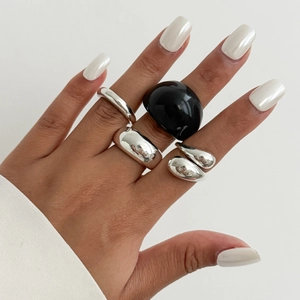 Detail van zilveren druppelringen en zwarte harsring voor een minimalistische modieuze look