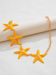 Macro detail of golden starfish waist chain with vibrant yellow enamel finish