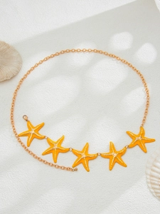 Detail of golden waist chain with five vibrant orange starfish pendants on a white surface