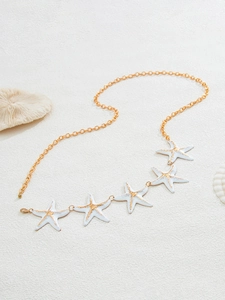 Detailed close-up of golden starfish waist chain with white enamel and coral beach decor