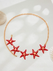 Detail of gold starfish waist chain with red enamel charms and secure lobster clasp closure