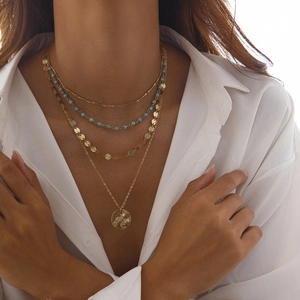 Collier multicouche doré avec pendentif pièce de monnaie et perles porté par un mannequin