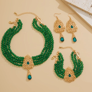Vista macro del conjunto de joyas doradas vintage con cuentas verdes y cristales esmeralda