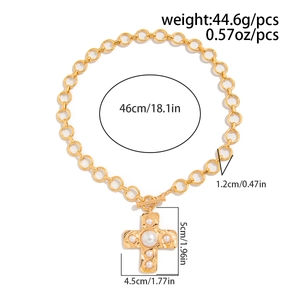 Detail of gold chain necklace with textured cross pendant and white pearl accents