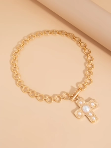 Detail of a gold cross pendant with pearls and T-bar toggle clasp on a chain necklace