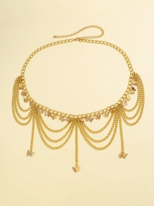 Détail d'une chaîne de taille dorée multicouche avec breloques papillon et franges