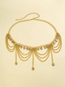 Détail de la chaîne de taille dorée multicouche avec pendentifs cœurs et pompons à franges