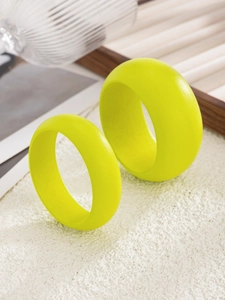 Nahaufnahme matter fluoreszierend grüner breiter Armreifen auf einem Holztablett