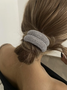 Vue macro d'un anneau de cheveux argenté serti de strass fixé sur un chignon
