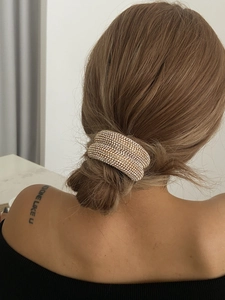 Détail d'une pince à cheveux de luxe en strass avec base dorée sur un chignon bas