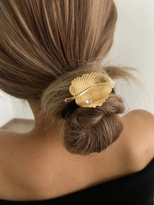 Accessoire cheveux feuille dorée avec strass sur chignon bas pour un look élégant