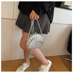 Detail of silver shell-shaped clutch bag with textured metal finish and chunky chain strap