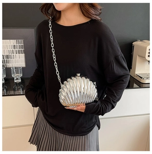 Chic silver shell-shaped metallic crossbody bag shown on model with sleek chain strap