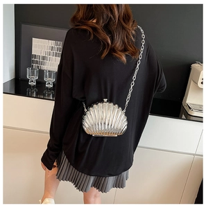 Detailed back view of a silver shell-shaped acrylic clutch with a slim metal chain strap