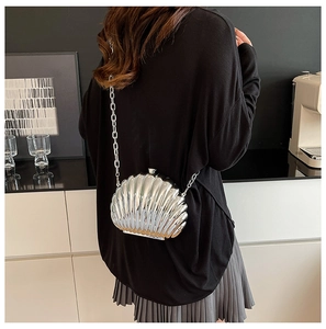 Detailed view of silver shell-shaped metallic crossbody bag with mirror-finish texture