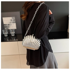 Detail of silver shell-shaped clutch bag with ridged texture and metallic chain strap