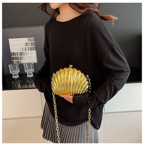 Close-up of golden shell-shaped clutch featuring metallic textures and a metal chain