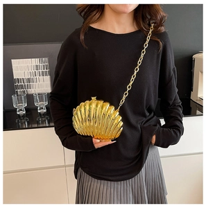 Detailed close-up of a golden shell-shaped evening bag with metallic texture and chain