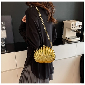 Chic gold shell clutch bag with metallic texture and chain strap in a lifestyle setting