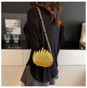 Detail of a gold shell evening clutch with metallic texture and chunky chain strap