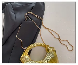 Detailansicht einer goldenen Designer-Abendtasche auf einem grauen Sakko mit Kette