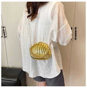 Detail of a golden shell evening clutch bag with pearl trim and gold chain strap