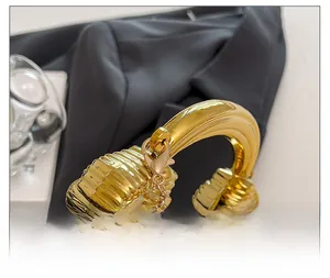 Detail einer goldfarbenen Tasche mit strukturierter Oberfläche und rundem Metallgriff