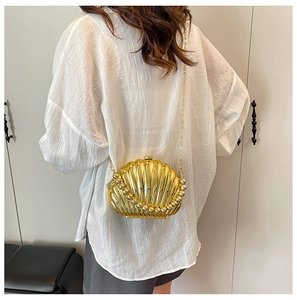 Detailed shot of golden shell-shaped clutch featuring pearl edge trim and chain strap