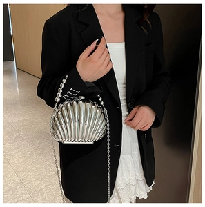 Detail of silver shell-shaped clutch bag with pearl handle and metallic chain strap