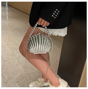Detail of silver shell-shaped evening bag with beaded handle and metal chain strap