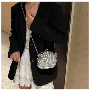 Detail of silver shell-shaped evening bag with metallic finish and delicate chain strap