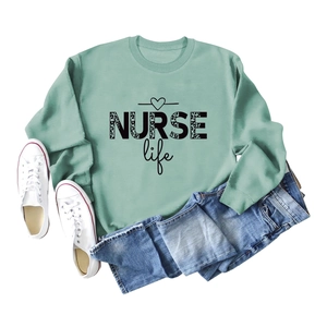 Flat lay of sage green NURSE life sweatshirt with leopard print and casual accessories