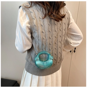 Details einer türkismetallischen Tasche mit Muscheltextur und goldener Kette am Model