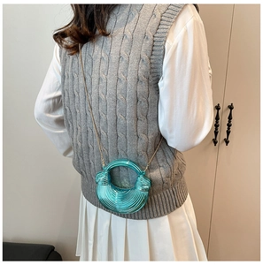 Detail einer metallisch blauen Mondsichel-Handtasche mit Wellenstruktur und goldener Kette