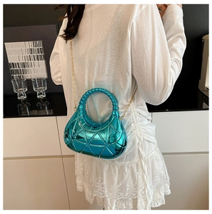 Détail du sac sous l'aisselle bleu métallisé avec gaufrage et bandoulière chaîne dorée