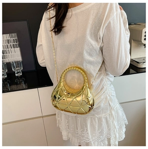 Détail du sac à bandoulière rigide doré avec texture géométrique 3D et bandoulière chaîne