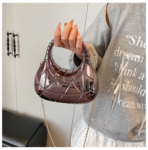 Détail d'un sac sous les bras en métal violet avec motifs géométriques et chaîne dorée