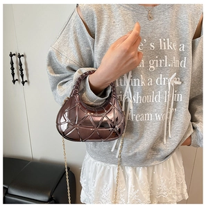 Détail du sac croissant en cuivre montrant des motifs géométriques et la chaîne