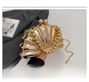 Détail du sac de soirée doré en forme de coquillage avec poignée en perles