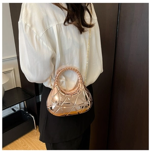Détail d'un sac géométrique ajouré or rose avec chaîne en métal porté par un mannequin