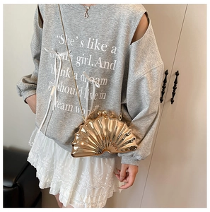 Pochette dorée brillante en forme de coquillage avec bandoulière et tenue décontractée