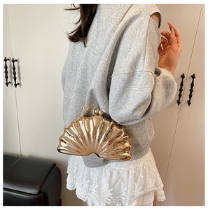 Détail du sac de soirée coquillage doré avec texture radiale et fermoir boule