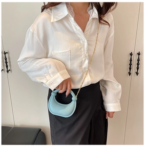 Close-up of light blue mini crescent bag with gold chain strap and ring knot handle detail