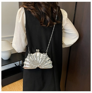 Pochette argentée en forme de coquille avec perles et chaîne portée par un mannequin
