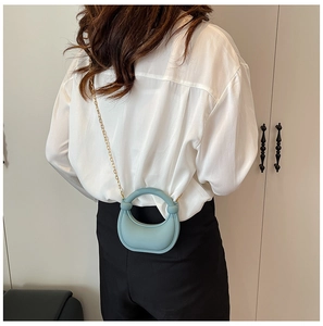 Model view of a light blue mini semi-circular bag with a gold chain and ring handle