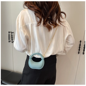 Blue mini crossbody bag with gold chain strap shown on model to display compact size