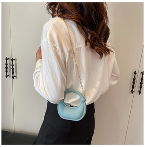 Detailed view of light blue crescent mini bag with gold chain strap on a model shoulder