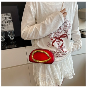 Chic red evening clutch with gold metal ring detail and fine chain strap shown on model